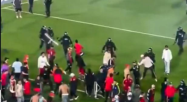 Háború a futballpályán: botokkal, székekkel estek egymásnak a szurkolók, a rendőrök rohampajzzsal és könnygázzal oszlattak – videó