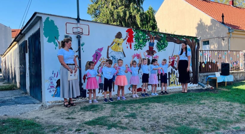 Színes grafika költözött a hatalmas tűzfalra – az ovi mellett garázs oldala jó kedve hangol