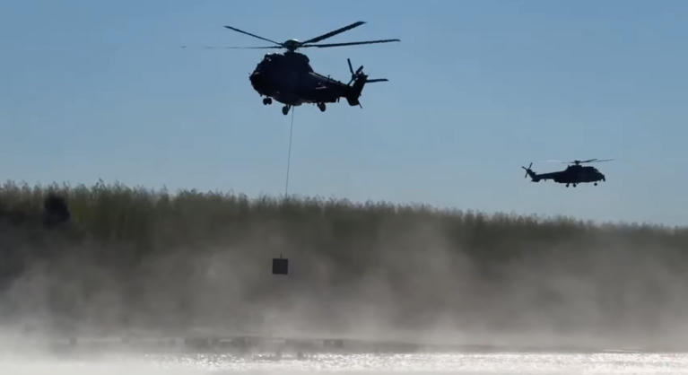 Katonai helikopterekkel helyeznek betonkockákat a Dunába Paksnál, videón a látványos művelet